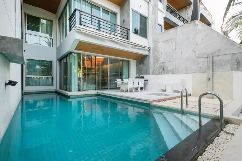 Modern backyard with a sleek in-ground pool and contemporary home exterior, featuring large glass sliding doors, outdoor seating, and minimalist design elements for a luxurious outdoor living space.
