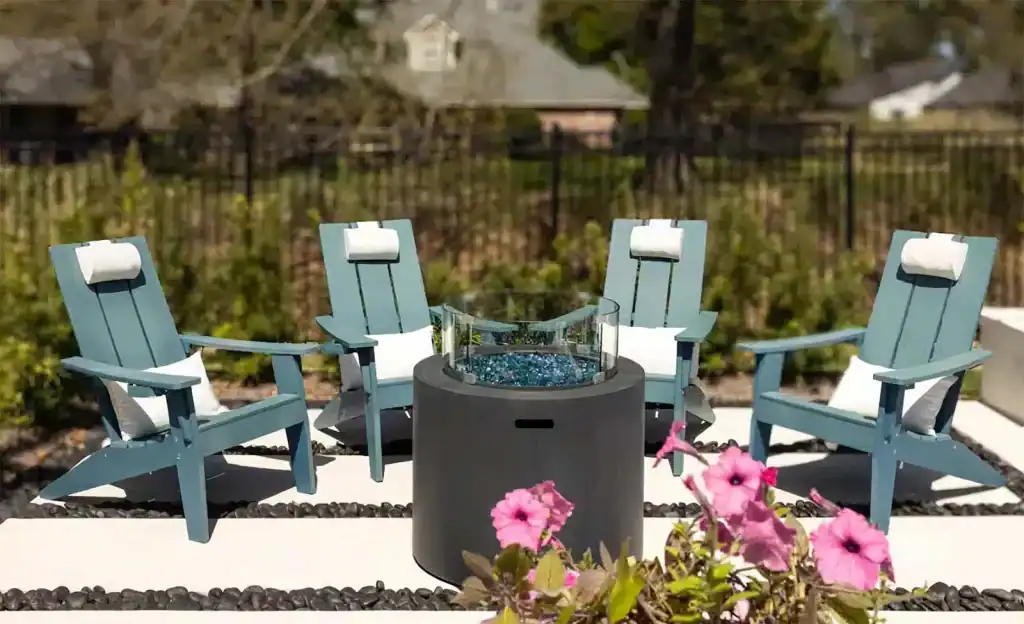 Stylish outdoor seating area with three blue Adirondack chairs and a modern fire pit, perfect for relaxing by the pool and enjoying outdoor gatherings in a beautifully landscaped backyard.
