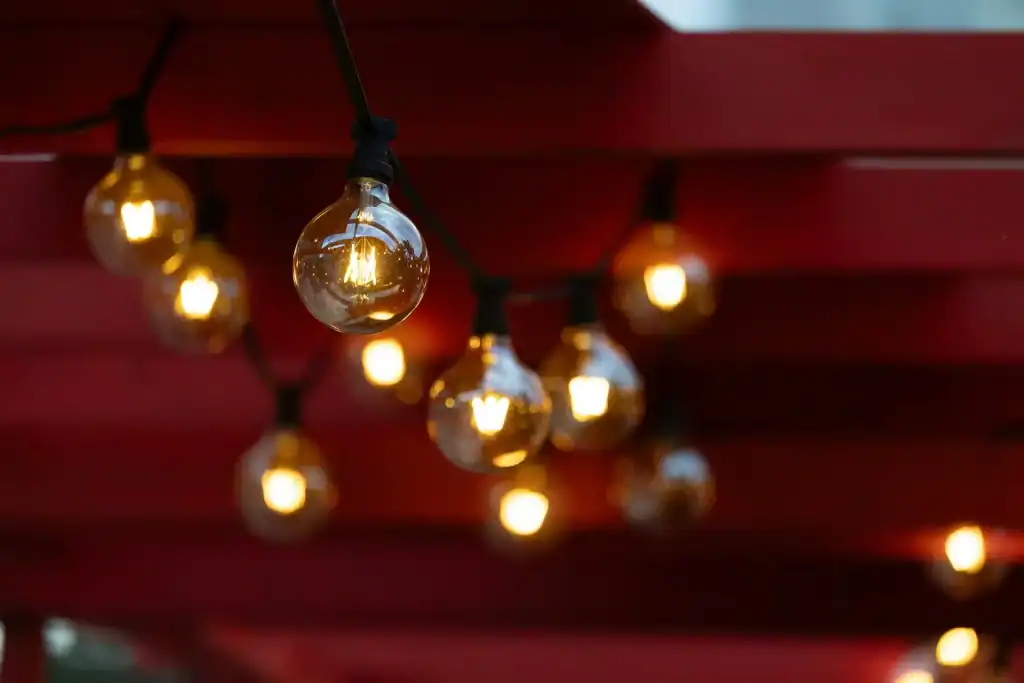 Warm string lights hanging against a red ceiling create a cozy, inviting atmosphere perfect for outdoor poolside entertaining and enhancing your backyard oasis.