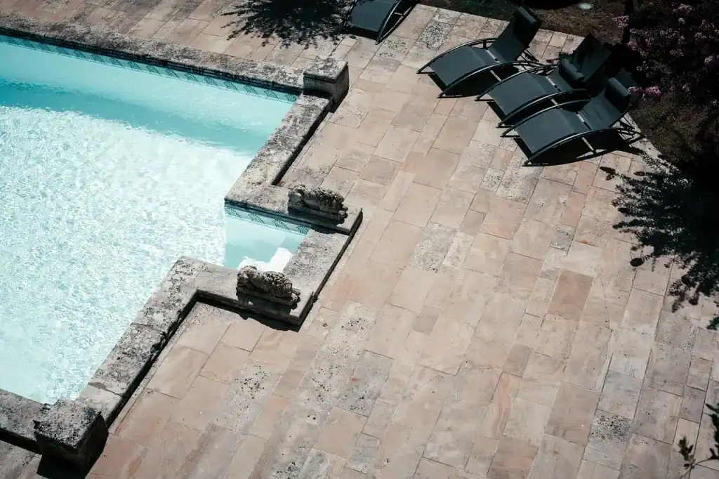 Luxurious backyard pool with elegant stone deck and lounge chairs for relaxing. Perfect outdoor space designed by Duplessis Builders for your dream pool experience.
