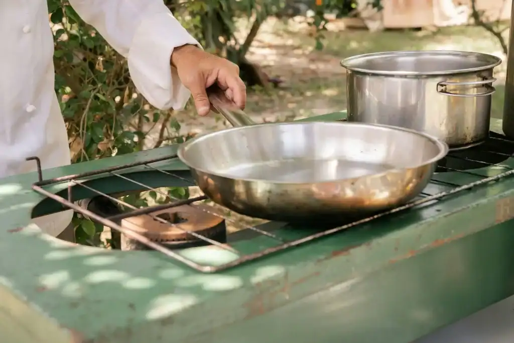 Clean outdoor kitchen with stainless steel pans and green wooden countertop, ideal for summer cooking and poolside entertaining.