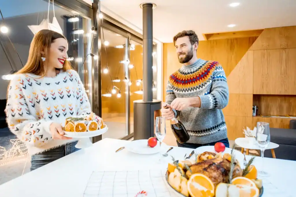 Beautiful couple celebrating Christmas indoors, with festive decorations, enjoying holiday treats and champagne, creating joyful holiday memories.