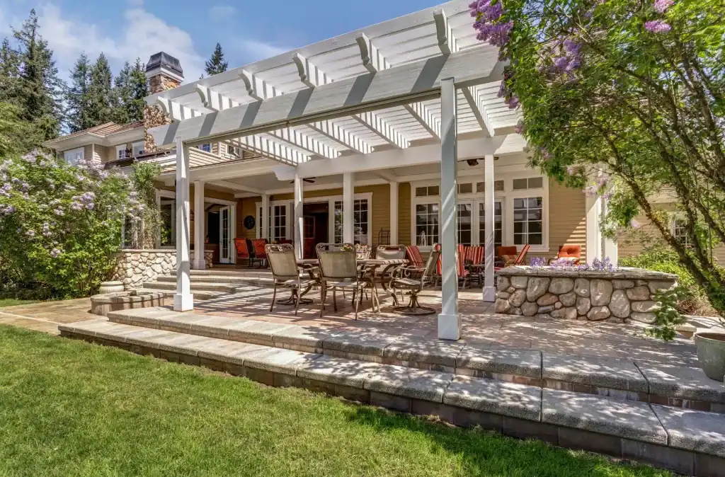 Beautiful backyard with a spacious covered patio, elegant outdoor dining area, and lush landscaping, perfect for relaxing and entertaining.