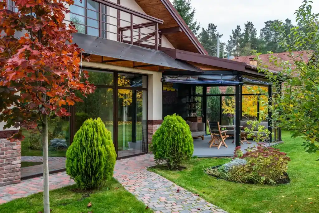 Beautiful backyard with a screened-in porch, lush green lawn, colorful trees, and stylish outdoor furniture, showcases a perfect space for relaxation and outdoor living.