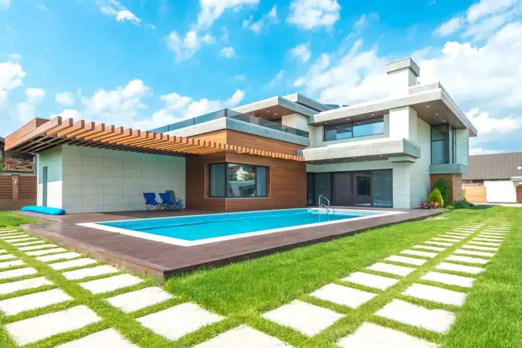 Luxurious modern backyard with a sleek swimming pool, wooden deck, and stylish contemporary house design under a bright blue sky. Perfect for outdoor living and entertaining.
