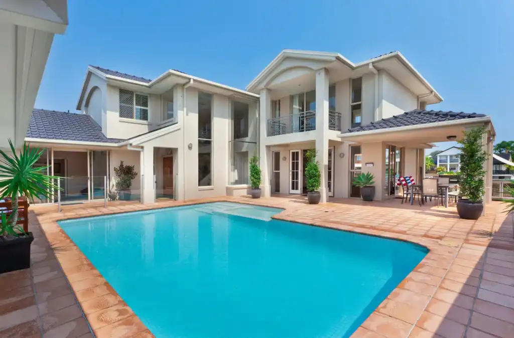 Stunning modern backyard with a luxurious blue swimming pool, surrounded by a spacious patio and lush potted plants, perfect for relaxing and outdoor entertaining.