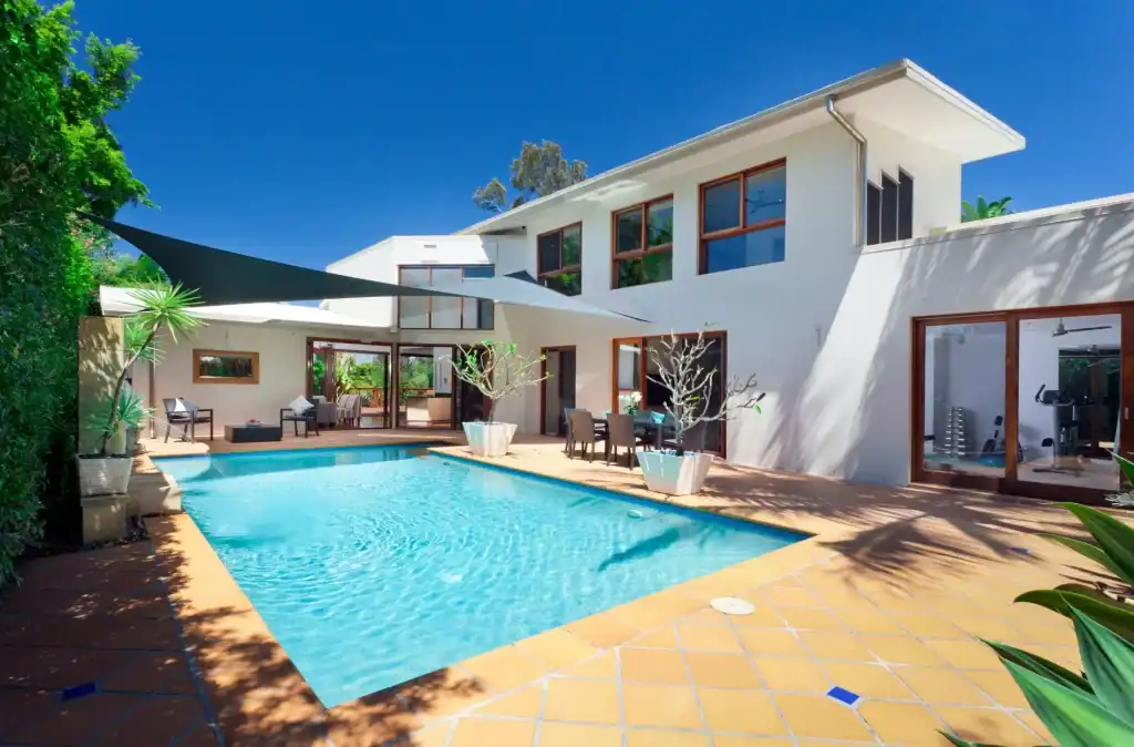 Luxury modern backyard pool with a sleek design, surrounded by a stylish patio and lush greenery, perfect for relaxation and outdoor entertainment.