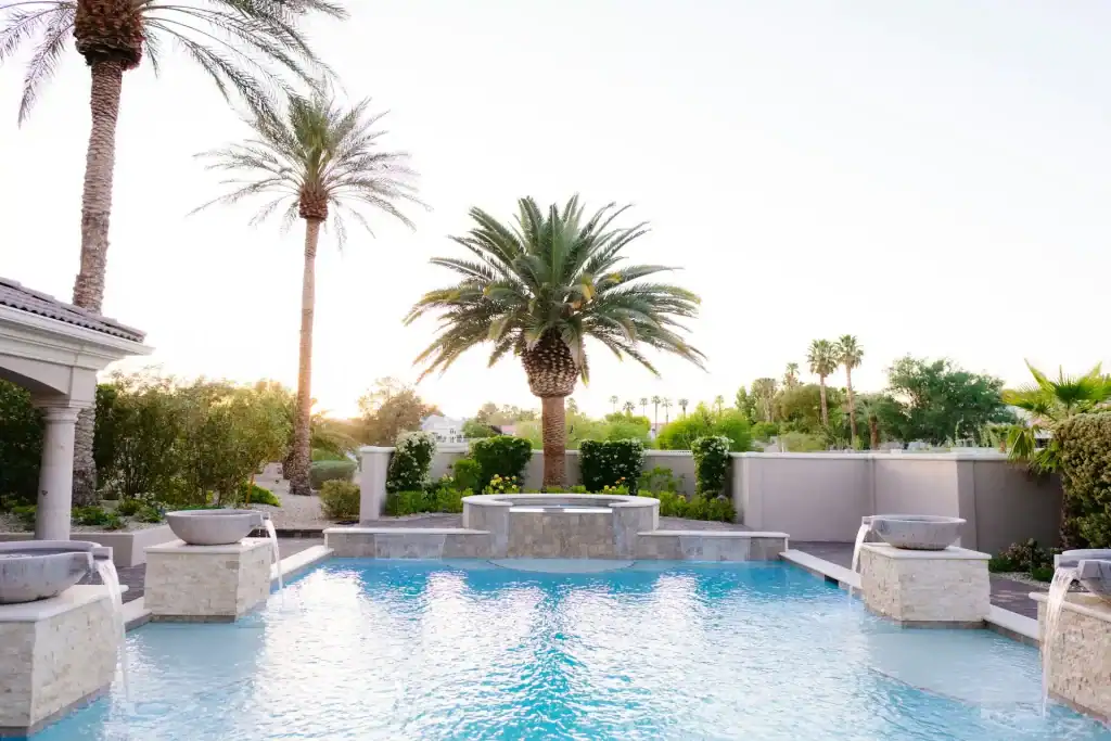 Lush backyard with a beautiful swimming pool, tall palm trees, and vibrant landscaping, creating a relaxing and luxurious outdoor space for entertaining and leisure.