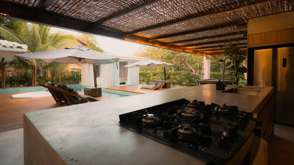Luxurious poolside retreat with sunbeds, umbrellas, and tropical landscaping designed for leisure and outdoor enjoyment. The scene includes a stylish pool, wooden deck, and surrounding lush foliage, ideal for summer relaxation.