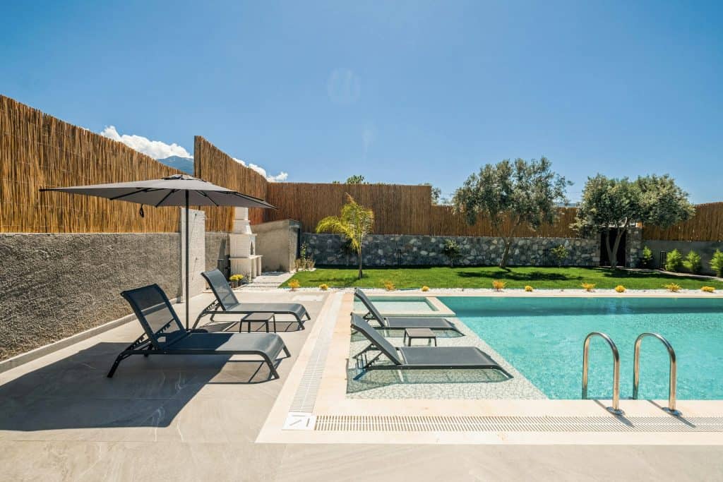 Modern backyard swimming pool with lounge chairs, umbrella, and landscaped yard for outdoor relaxation and entertainment.