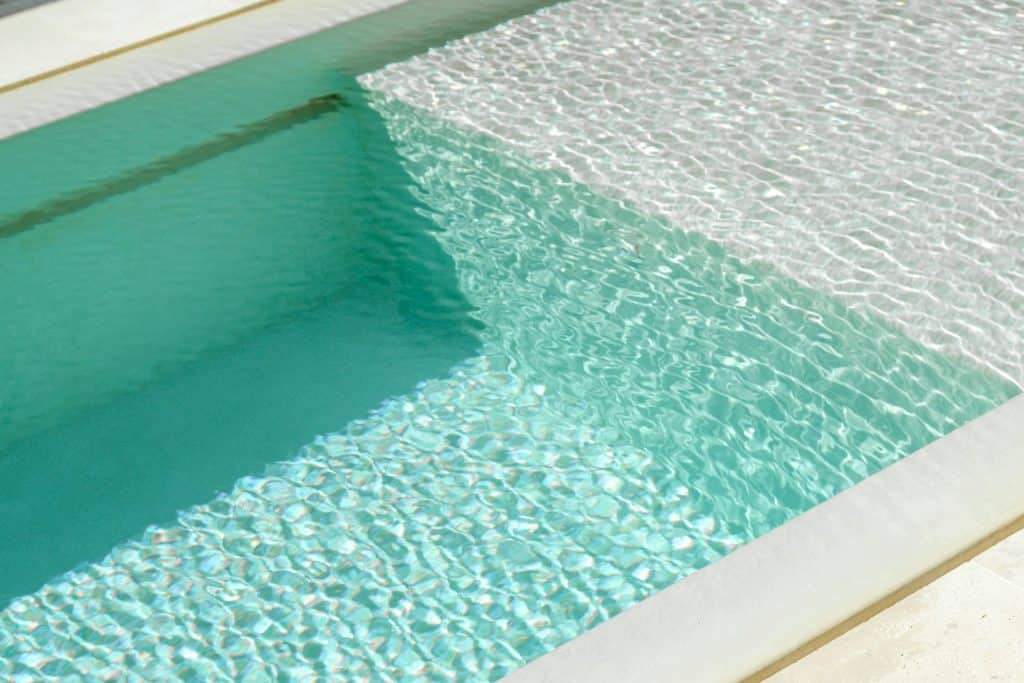 Beautiful modern pool with clear blue water and textured mosaic accents, perfect for backyard luxury and relaxation.