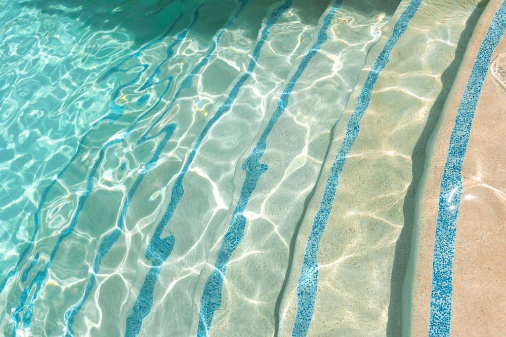 A beautiful, inviting pool featuring clear water and vibrant blue tile lines, perfect for relaxing and enjoying outdoor leisure activities.
