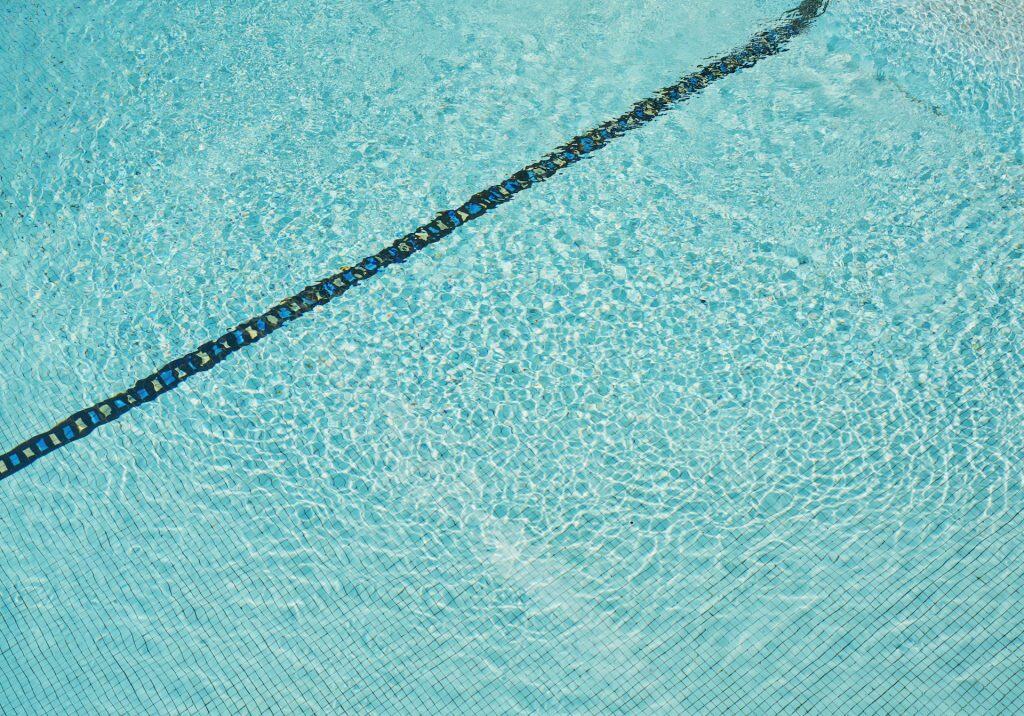 Aerial view of a sparkling blue swimming pool with a dark lane marking, showcasing a sleek and modern design perfect for backyard retreats.