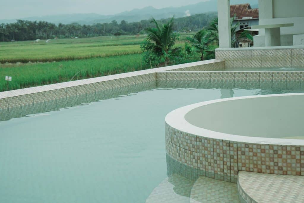 Gorgeous custom swimming pool with mosaic tile accents overlooking lush green fields and distant mountains, perfect for leisure and outdoor gatherings.