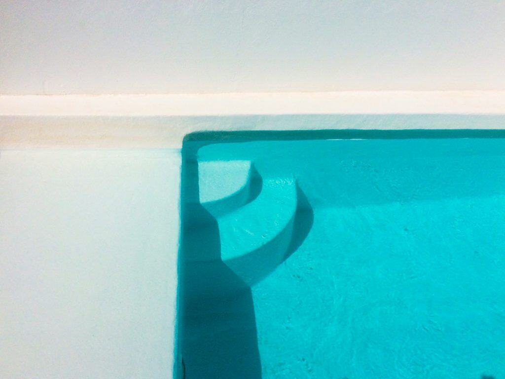 Close-up of built-in pool stairs with vibrant blue water and white pool walls for a luxurious swimming experience.