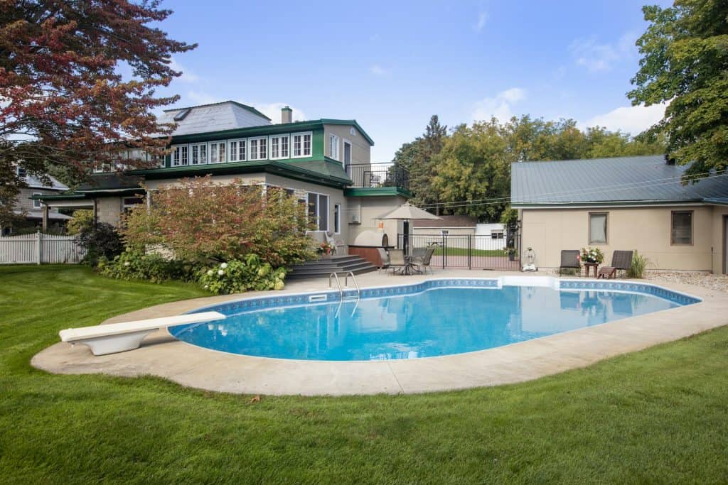 Luxury in-ground swimming pool with clear blue water, landscaped backyard, and outdoor seating area, ideal for enjoying warm spring days in Baton Rouge.