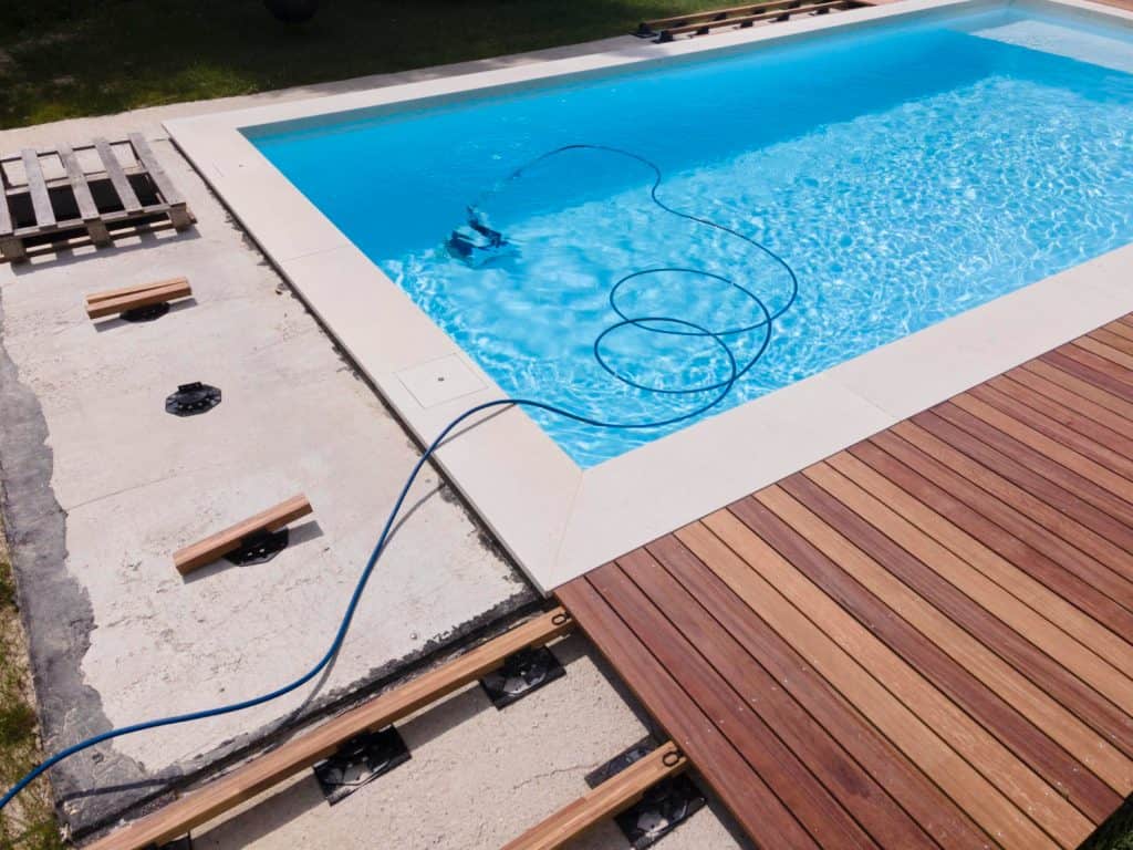 Image of a newly constructed swimming pool in Baton Rouge with a wooden deck, showing ongoing installation and preparation for warm months.