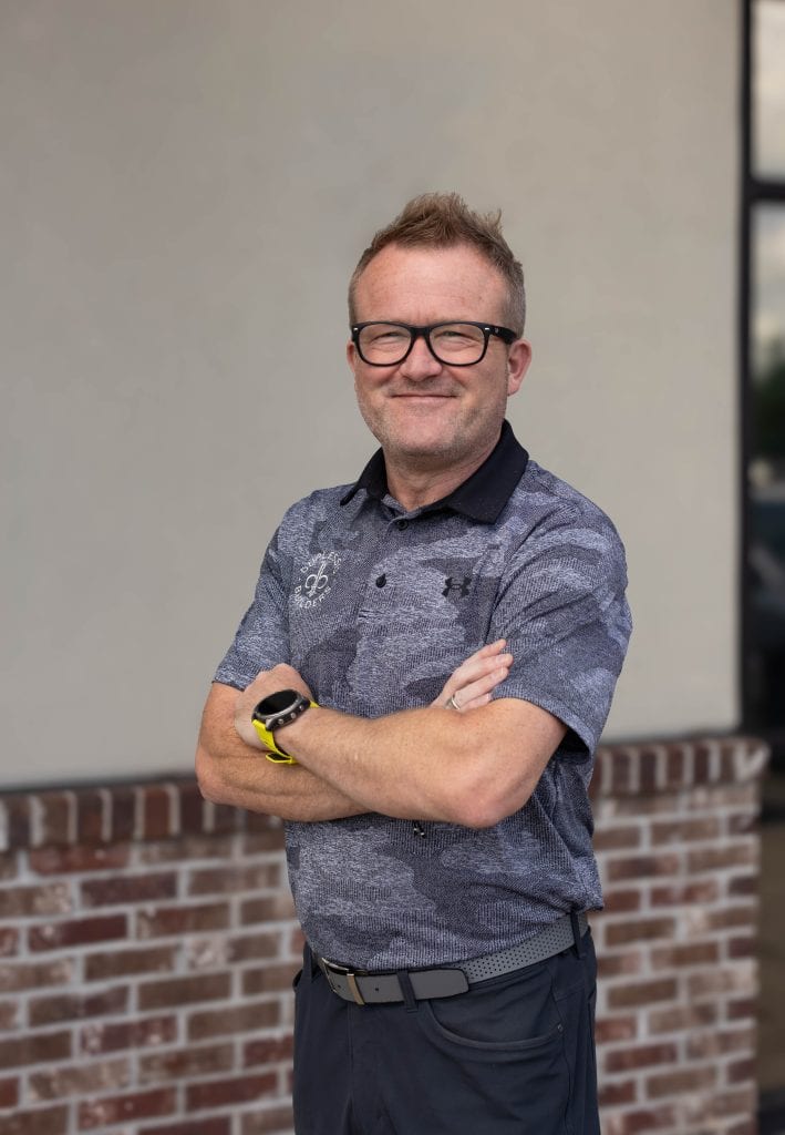 An experienced pool builder smiling confidently outside, wearing glasses and a casual polo shirt, representing Duplessis Builders' commitment to quality pool construction.