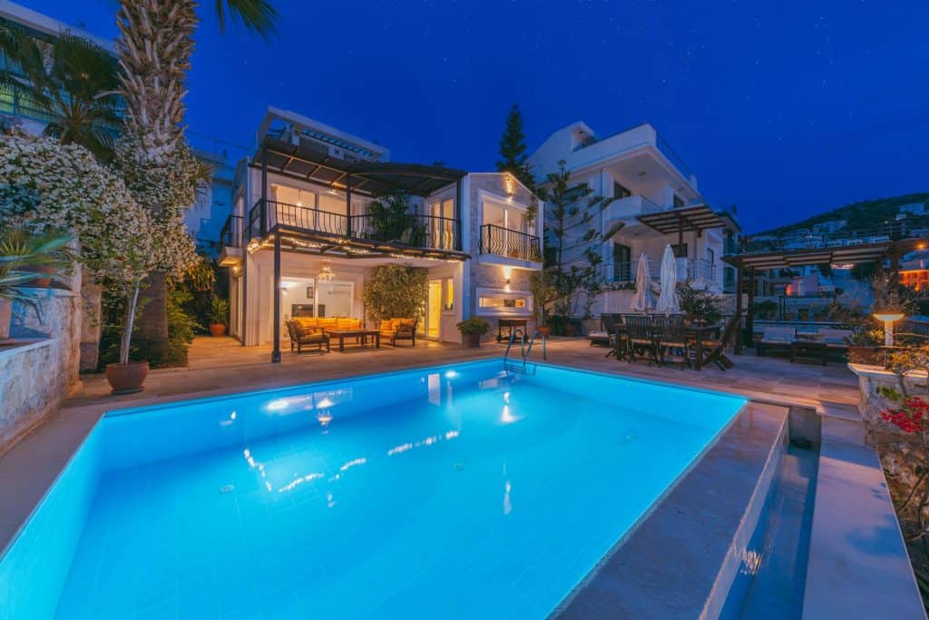 Beautiful illuminated swimming pool in a luxury modern home setting during nighttime, showcasing elegant architecture and outdoor living space.