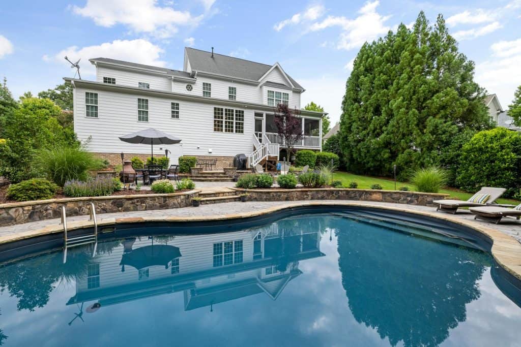 Beautiful backyard pool featuring a sleek design, surrounded by vibrant greenery and comfortable seating areas for relaxing outdoor experiences.
