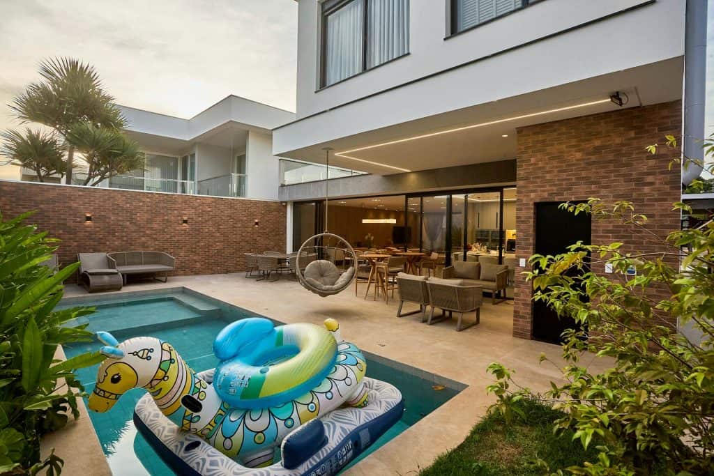 Contemporary backyard featuring a swimming pool with colorful inflatable toys, outdoor lounge chairs, and a cozy seating area under a covered patio, perfect for relaxation and entertaining.