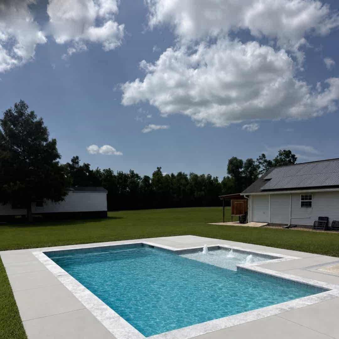 Custom gunite pool and spa behind a white farmhouse-style home in the Baton Rouge area
