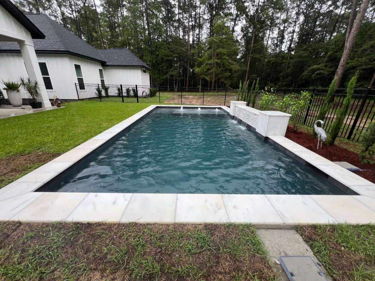 Permanent black aluminum pool safety fence enclosing a finished backyard pool in Baton Rouge