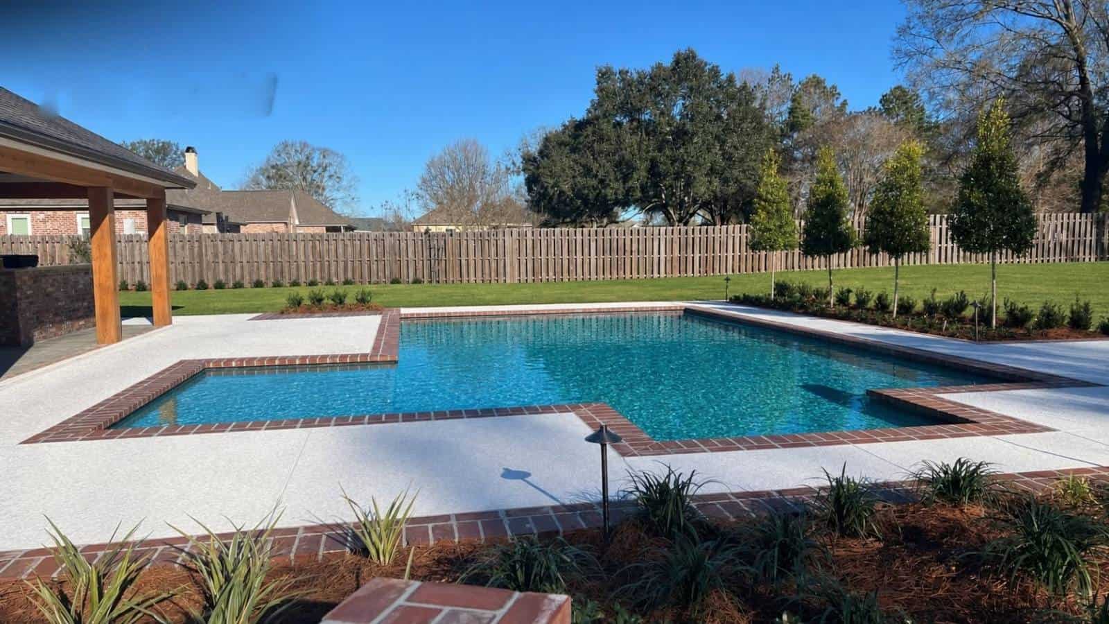In-ground pool with brick coping beside a covered patio at a Baton Rouge home