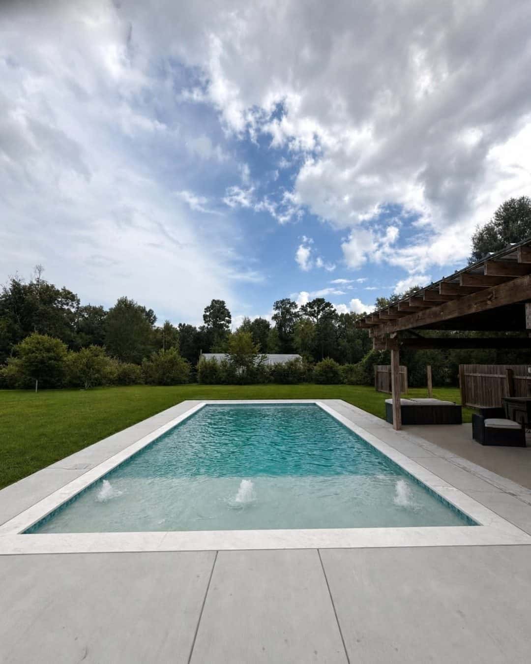 Rectangular pool with wooden pergola and outdoor furniture in Prairieville, Louisiana