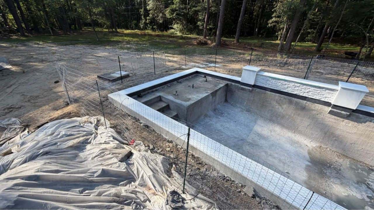 Temporary wire safety barrier surrounding a gunite pool shell during construction in Louisiana